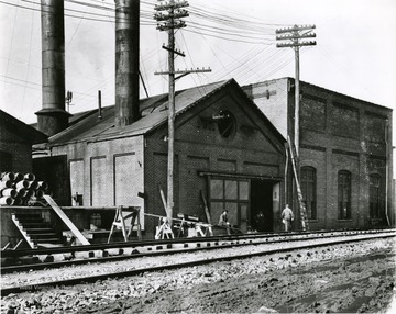 Factory located near the railway tracks in Morgantown, W. Va.  Workers seen near the bay door of factory. 