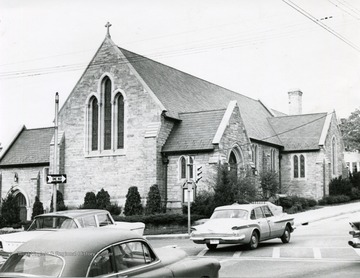 Exterior of Episcopal Church located in Morgantown, W. Va. Cars driving by Church on a one way street. 