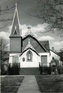 'Taken by Roy T. Emerson 1950 for Trinity Women's Auxiliary Yaar Book' Letter enclosed reads: ' July 1, 1959   To Whom it May Concern: Enclosed please find snapshot of Trinity Episcopal Church taken in 1950. This picture was used on  yearbook of Trinity Women's Auxiliary. In the year 1950. Trintiy was sold to a Church group, dismantled and moved board by board to their Church property near B--? W. Va. This over the forth or fifth move for this Church building. Trinity Church was purchased by first Vestry from the Baptist Church, before this time the Episcopal services were being read in old Rogers' home. The church stood at top of High Street before street was paved. With a great deal of effort it was finally moved to spot where New Farmers and Merchants Bank is now going up; however during move a rain storm hit and Church got bogged down in mud and stood in the middle of High Street for several weeks before ground was solid enough to prepare another attmept. The church was moved later, as shown in Post picture to spot next to Masonic temple and the place where Trinity Parking lot is now. This is the tale as told to me by Brad Laidley for most accurate account contact him. Sincerely, Monica Emerson, New Timer?'