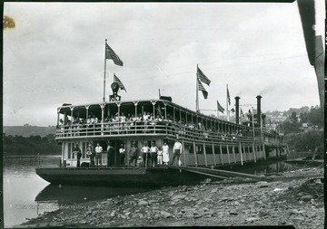 People stand at the side rails on the showboat at the wharf.