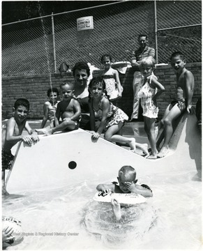 A woman and a group of kids are in the kiddie pool.