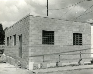 Construction of an unknown building in Morgantown, W. Va. Cinder blocks seen laying on the ground holding boards that make a fence. 