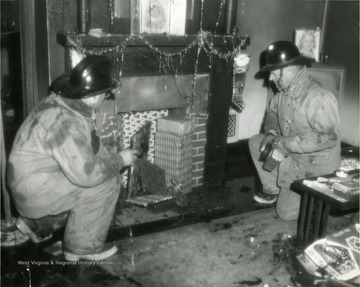'Firemen in a residence extinguishing a fire'. Decorations imply it was Christmas time at the time of fire. 