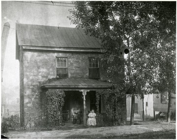 A woman sits on the porch of the Old Stone House.
