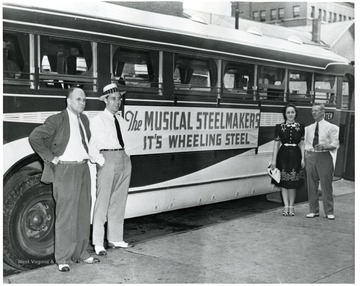Four people are standing outside a Wheeling Steel, the Musical Steelmakers, bus, in Wheeling, West Virignia.