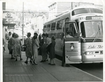 A bus from the Lake Shore System is dropping off some passengers at a bus stop on High Street in Morgantown, West Virginia.