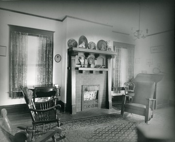 The interior of a residence in Morgantown, W. Va. Photos and other items located on the mantle above the fire place. Furniture is rocking chairs; some wooden and some upholstered. 