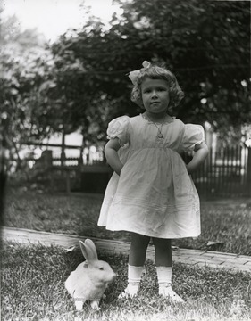 A young girl has her picture taken with a rabbit. 