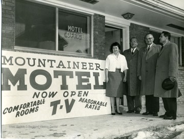 Three gentlemen and a lady are standing in front of the Mountaineer Motel office in Morgantown, West Virginia.