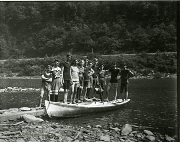 Men and women standing on a canoe which is docked in Morgantown, West Virginia.