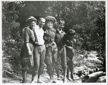 Five men and women standing on a rock.