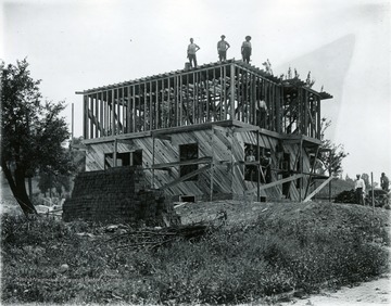 Men seen standing on the unfinished construction project. Lower story already structured, working on second story.  