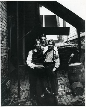 Three boys sitting on a barrel. 'Harry Selby is on the right.'