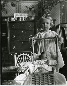 A young girl is pushing a baby in a carriage in a house in Morgantown, West Virginia.