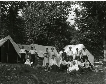 Several men and women are posing for a group portrait in front of three tents at a campsite in Morgantown, West Virginia.