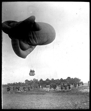 World War I Lantern Slide Show. In group of originally numbered slides.  (Number label is lost.)  American observation balloon near ground.  There are several soldiers in the ballon basket, and groups of soldiers on the ground.  Frame is labelled with text saying 'Visual Bureau, University of Pittsburgh.'  (negative no. 46-9784 is inscribed on slide)<br /><br />