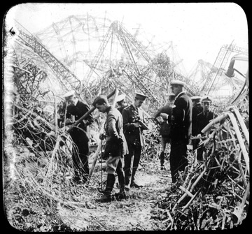 World War I Lantern Slide Show. In group of originally numbered slides.  (Number label is lost.)  Wreckage of Zeppelin airship under inspection by soldiers.  Frame is labelled with text saying 'Visual Bureau, University of Pittsburgh.'<br /><br /><br />