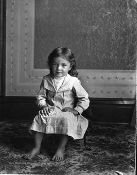 A young girl is sitting on a stool in a house in Morgantown, West Virginia.