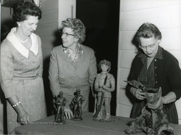 Women present for this Sundale Membership Coffee Meeting are 'Mrs. Harry Muffly, and Mrs. J.O. Knapp', third woman unidentified. Women stand looking at statues. 