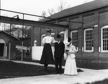Two women and a man are standing in front of the Morgantown Power Plant.