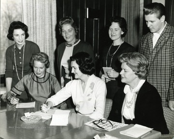 Six women and a man with paperwork relating to the Womens Golf meet at Lakeview in Morgantown, West Virginia. 