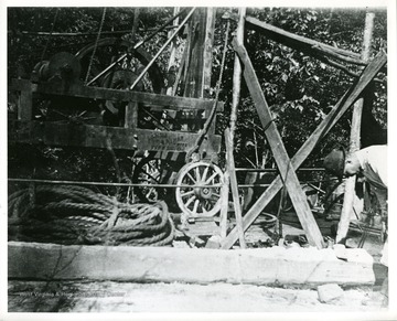 A gentleman is working with an early oil rig in Volcano, West Virginia.