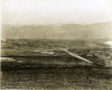 'Morgantown Ordnance Works, Morgantown, W. Va. Photograph Number 105. From left to right foundation work on factory building, maintenance shops and stores, service and main office building. Grading in the power recovery area appears in the left background. Looking East. February 13, 1941, 10:00 A.M.'