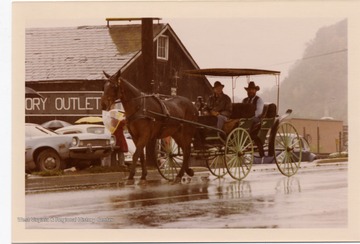 On a rainy day, a horse is pulling a carriage with two men during the Monongalia County Bicentennial Parade in Morgantown, West Virginia.