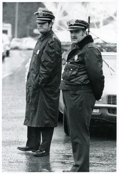 Two police officers, one identified as Ralph D. Chapman, stand in front of a car.