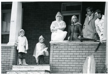 People stand on a porch to watch the parade.