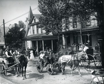 Horse-drawn wagons decorated with flowers seen in parade. 