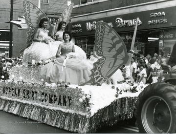 Three ladies sit atop the 'Morgan Shirt Company Float' in the Labor Day Parade. 