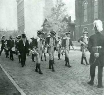 Men in colonial costume marching in a parade. 