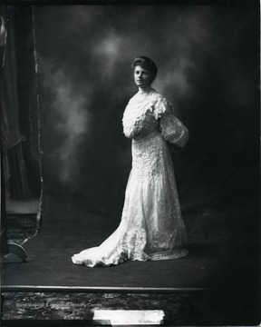 A woman poses for a portrait wearing a white dress. 'Source: Hugh Knee.  Knee also worked in New York. These photos may date to that time.'