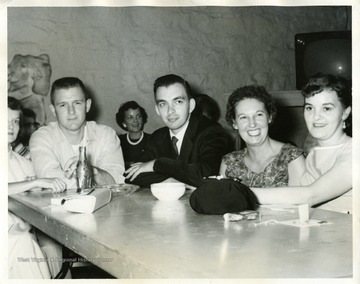 'Watching square dancing in brass room. From left to right: Mrs. Raymond Bowers, Mr. Bowers, Don Longfellow, Mrs. Anna Jean Shultz, and Mrs. Catherine Coda. In the background is Mrs. Betty Sodomick. Longfellow is Superintendent over Turret Automatics, and Tube Mill. Both Mr. Bowers and Mrs. Shultz are employed in the Tube Mill.'