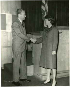 Robert W. Dinsmore shakes hands with an unidentified woman.