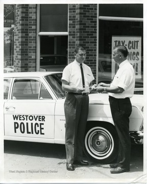 Joseph J. Janco, Mayor of Westover, is standing with an unidentified man in front of a Westover Police car.