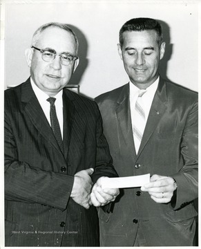 'Donald F. Riedeman, Chairman of the Marion County Heart Committee, is shown on the right present a $2,000 grant to the West Virginia University School of Medicine for research of the genetic aspects of congenital heart disease. Dean Clark K. Sleeth accepts the check for the study.'