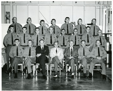 'Greenbrier Front Line Firefighters....Nineteen graduates pose after receiving Certificates of Merit from Ray A. Simpson (third from left, seated), Field Instructor, Fire Service Extension of West Virginia University. These Security Officers have passed a course in Fire Prevention and Training under the supervision of Harry Welch, Chief Security Officer at The Greenbrier. This is the second diploma given these men as they have also completed a course in Police Practice and Procedure offered by Marshall University. (left to right) Front Row: Eugene Camp, Merle Morgan, Ray A. Simpson, Mr. T. Keenan-Manager at The Greenbrier, R.E. Hanna, Major Allen Terry and William Sulser. Second Row: John Smith, Robert E. Craft, Beuford R. Bennett, Porter George, Sgt. Charles B. Feury, Carlos Hefner, George F. Masters and Robert Burgess. Third Row: Sgt. Thomas Z. Henson, Donald C. Ford, Clyde Moxley, Donald R. Williams, George Gillespie, George M. Wikle, and Cline G. Welsh.'