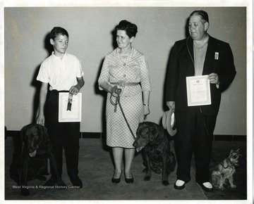 Three participants of the Seeing Eye Dog program are shown with their partmers. Left to right: young boy, Louise Keener, and Mr. Thomas.