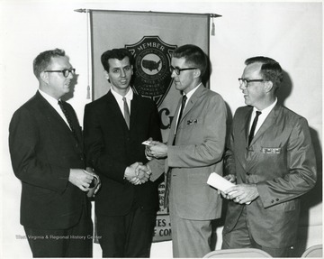Neil E. Bolyard (far right) and Neil H. Coates congratulate a young man.