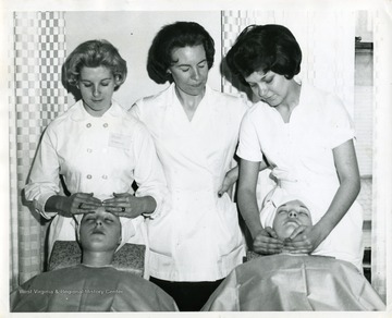 Two Beauty School Students work on clients as an instructor looks on.