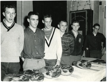 F.F.A members stand behind a table of hams.