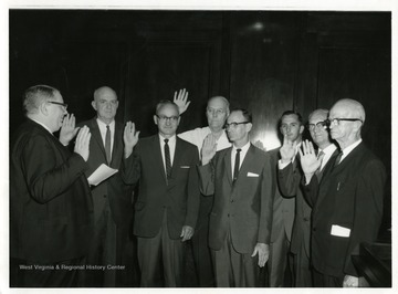 Right to Left: William Schumann, Paul Rrevillian, Jack Catlie, J.T. Jamison, S.S. Lynch, Unidentified, and Harold Wildman are being sworn in by City Clerk James Ashburn.