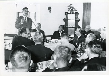 A speaker is talking to a group at a luncheon. J.W. Ruby, Jennings Randolph, and Orville Freeman, Secretary of Agriculture attended the luncheon.