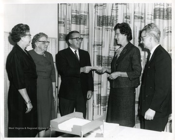 Ward Stone is either giving or receiving a check from Mrs. Leonard Sizer while two ladies and a gentleman looks on.