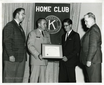 Mr. Zinn(right), Colonel Reynolds (second from right), and Foster Mullinax (far left) are presenting a plaque to Wally Reed.