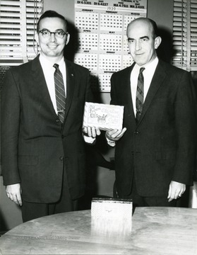 Two men holding a Claxton Fruit Cake.  On the right is Mayor of Morgantown Marlyn Lugar and on the left is Sandy Serpento.