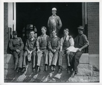 Men seated and standing in a entrance.