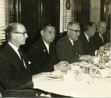 Five businessmen are attending a dinner. From left to right: Glen Zinn, Farmers 2nd Merchants Bank; George Switzer; L. Bush Swisher, Monongalia Power Company; Mr. McMillan, Monongalia Power Company; and Mr. Snyder, Hope Natural Gas.